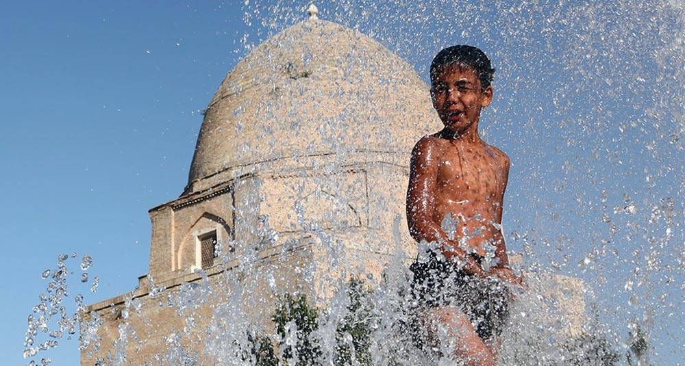 An 11-year-old boy finds relief from the summer heat by playing in a fountain in a historic part of the city of Samarkand, Uzbekistan. — courtesy UNICEF/Pirozzi