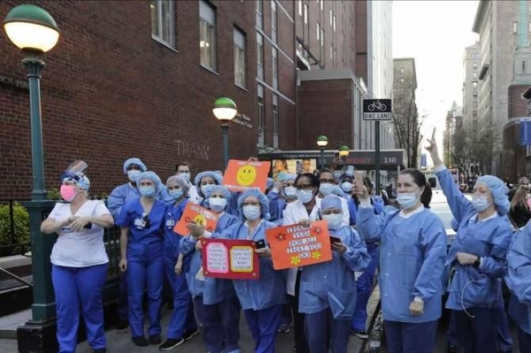 Nurses and medical workers react as police officers and pedestrians cheer them outside Lenox Hill Hospital in New York in this file photo
