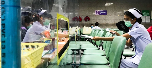 Nurses at a hospital in Bangkok, Thailand, exchange documents through acrylic shields that have been setup to ensure physical distancing. — Courtesy photo