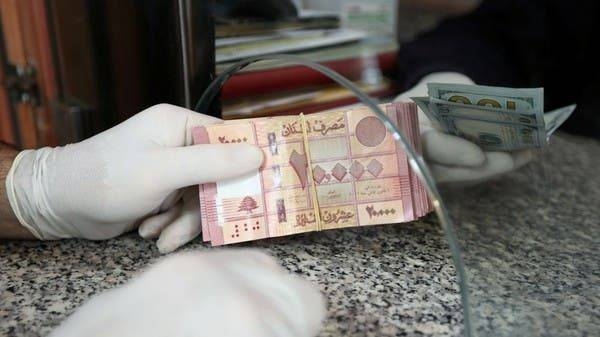 A customer wearing gloves holds Lebanese pound at a currency exchange store in Beirut. — File photo