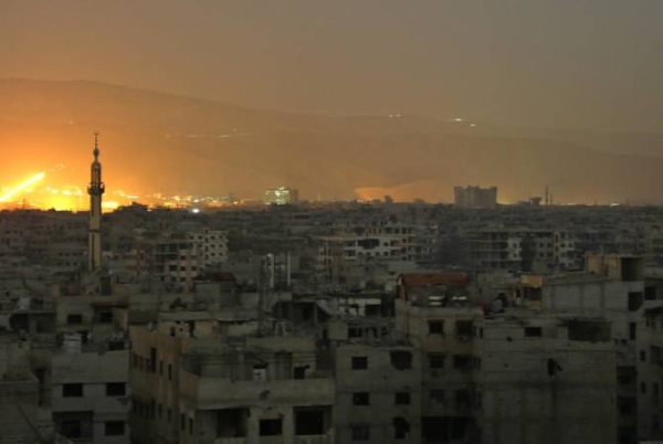 A general view shows smoke and flames rising from buildings following a reported Israeli attack on militant positions south of the town of Albu Kamal in Deir Ezzor province. — File photo