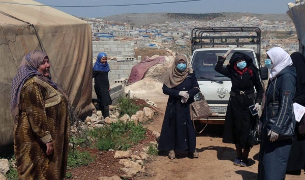 Standing on the left, a volunteer working to raise awareness on COVID-19 at an IDP camp in northern Idleb, Syria. Displaced from Homs herself, she knows the importance of helping protect the IDPs. — courtesy OCHA