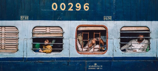 Passengers look out of the window as a train pulls into a railway station in Delhi, India. — courtesy Unsplash/Killian Pham