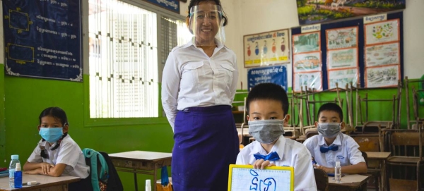 A teacher and her students practice COVID-19 school re-opening guidelines by wearing face masks and maintaining physical distance at a primary school in Phnom Penh, Cambodia. — Courtesy photo