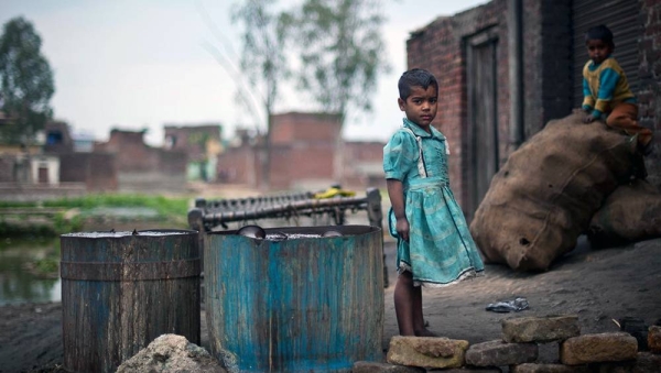 Children play outside a metal polishing workshop in a slum in Uttar Pradesh, India. — courtesy UNICEF/Niklas Halle'n