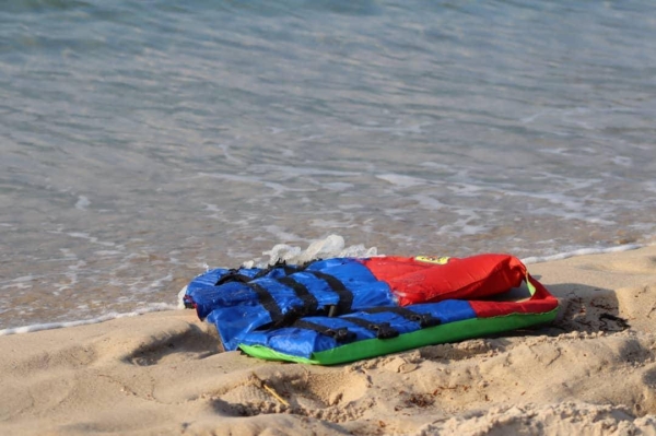 Life jackets litter a beach near the Libyan port of al-Khums as a rescue worker speaks with a survivor from a shipwreck. — Courtesy photo
