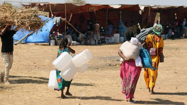 Recently arrived refugees from Tigray in Ethiopia bring supplies to help set up their shelter in Raquba camp, in Kassala, Sudan. — courtesy UNFPA/Sufian Abdul-Mouty