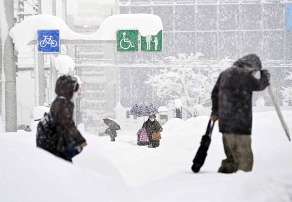 People walk on a snow-covered street in Toyama, central Japan, on Saturday, after heavy snow hit the region. — courtesy Kyodo