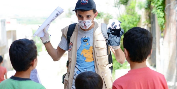 A young volunteer uses a hand puppet to educate children on COVID-19 awareness in northern rural Homs, Syria. — courtesy UNICEF/Abdulaziz Aldroubi