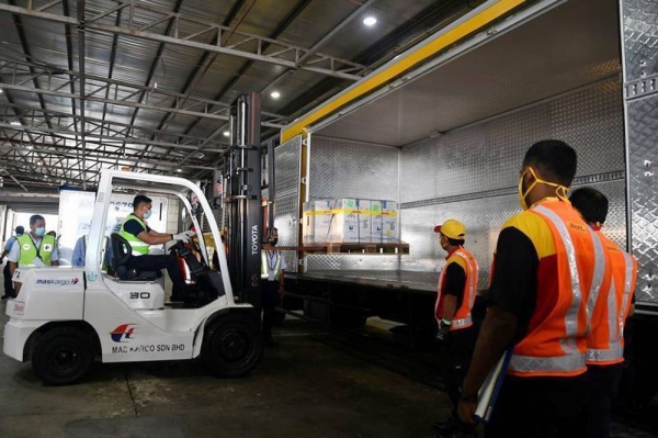Workers load containers carrying the first batch of COVID-19 vaccines into a truck at the MASkargo Complex in Sepang, Malaysia. Malaysia moved up its COVID-19 inoculation drive by two days as the first batch of vaccines arrived in the Southeast Asian nation on Sunday,