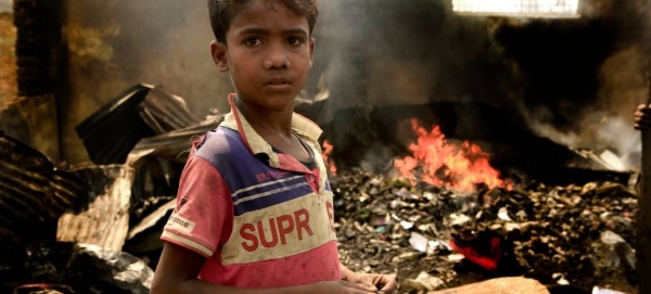 A 10-year-old child stands amidst debris at the Kutupalong refugee camp in southern Bangladesh. Behind him, the fire still burns, a day after the massive blaze tore through the camp. — Courtesy photo