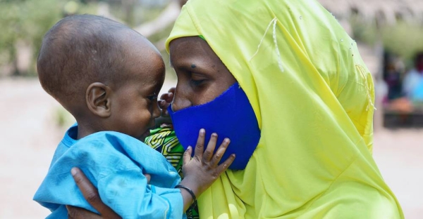 A baby plays with her mother’s mask at a nutrition support program in Bertoua, Cameroon. — courtesy UNICEF/Frank Dejongh