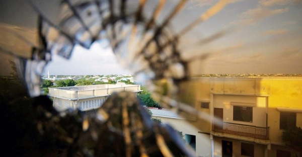 The skyline beyond the northern suburbs of Mogadishu is seen through a bullet hole in the window of a hotel in Somalia. — courtesy UN Photo/Stuart Price