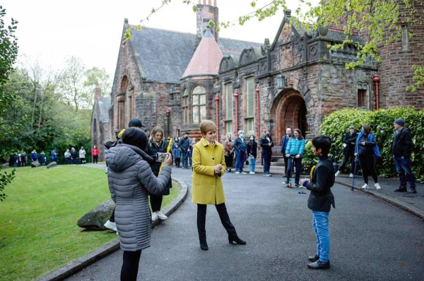 SNP leader Nicola Sturgeon see talking to a young boy as voters wait patiently in line at the Glasgow Southside constituency. — courtesy Twitter
