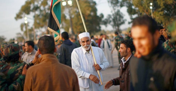 An old man holds Libya’s revived flag during a military graduation ceremony in the western city of Zawia. December 2011. — courtesy UNSMIL