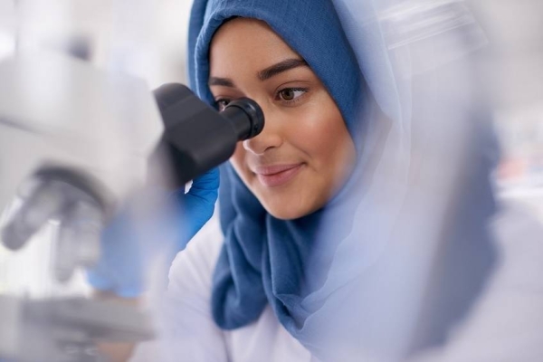 Shot of a young scientist using a microscope in a lab