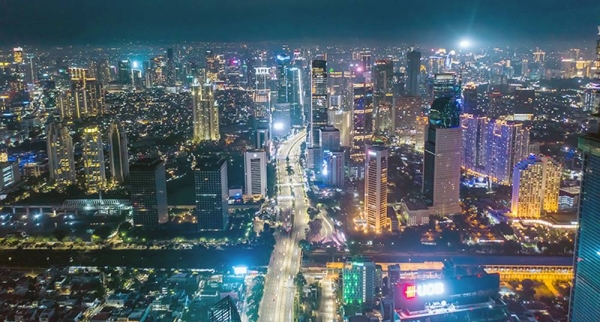 Aerial night cityscape of skyscrapers and multi lane highway traffic in modern city center of Jakarta. Indonesia has opened a few of its borders to foreigners following a ministerial regulation that reopens applications for tourist and limited stay visas for fully-vaccinated travelers.