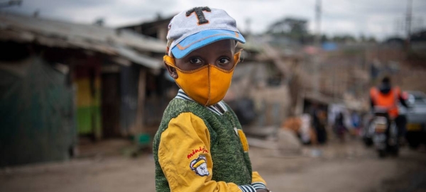 A young boy wears a face mask as he walks through Mathare, an informal settlement in Nairobi, Kenya.