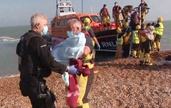 Rescued migrants are met with the British border patrol after arriving in Kent.