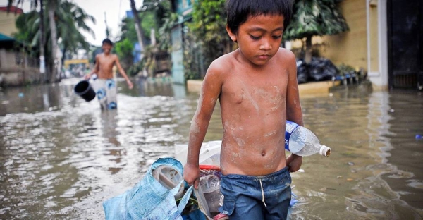 A boy drags possessions through the flooded streets of Manila in the aftermath of a typhoon. (file). — courtesy ADB