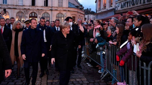 German Chancellor Angela Merkel and French President Emmanuel Macron, left, receive flowers and a bottle of wine as gifts as they are greeted by residents in Beaune, Burgundy.