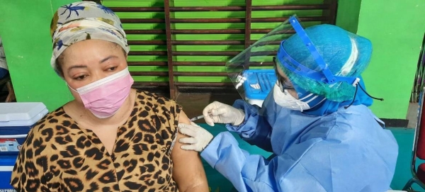 The Governor of DKI Jakarta together with UNHCR Indonesia Representative and members of KADIN (Indonesia Chambers of Commerce and Industry) observe a young refugee being vaccinated. — courtesy UNHCR Indonesia