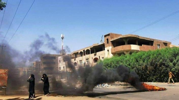 Sudanese women walk in front of tires set ablaze by anti-coup demonstrators in the capital Khartoum, following calls for civil disobedience to protest last month's military coup, on Sunday.