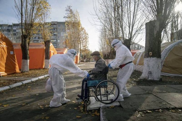 
Medical staff in protective gear transport an elderly patient suspected of having COVID-19 in a wheelchair at a tent hospital erected to care for coronavirus patients in Kakhovka, Ukraine, on Sunday, Nov. 7, 2021. — courtesy photo