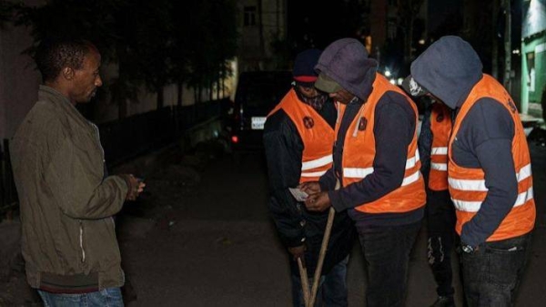 Volunteers check a man's identification card as they conduct night patrols in Addis Ababa, Ethiopia, on November 17, 2021. Volunteers have been patrolling the streets to check for 