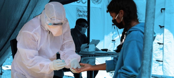 A health worker screens a young girl for COVID-19 at a fever clinic set up next to a hospital in Saptari District , Nepal.
