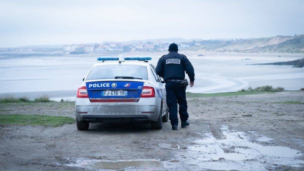 French police look out over a beach near Wimereux in France.
