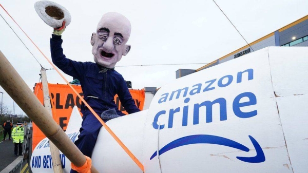 An Extinction Rebellion protester wearing a cartoonish Jeff Bezos head at the Tilbury, Essex Amazon center on Friday.