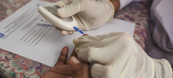 A health worker checks a woman’s blood sugar level at a community health center in Jayapura district, Indonesia.