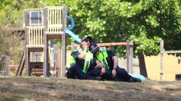 Two police officers comfort each other at the scene.