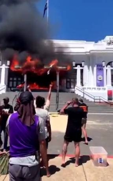 People stand in front of the burned out entrance doors to Old Parliament House in Canberra, Australia.