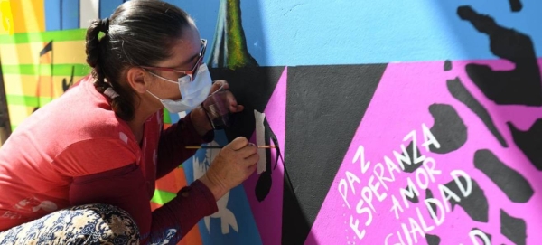 A woman paints a mural for Peace and Reconciliation in Colombia.