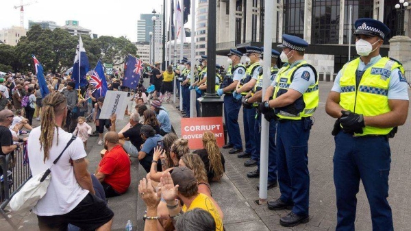 Police watch as protesters occupy the grounds around the parliament building in Wellington on February 9.