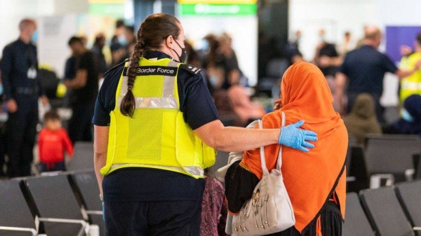 A Border Force officer helps an Afghan evacuee.