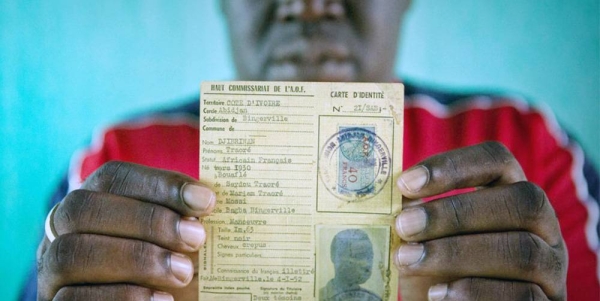 
A man identified as Oumar, who was at risk of statelessness, holds his father's identity card from French colonial times. — courtesy UNHCR/Hélène Caux