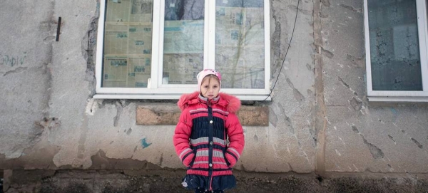 On Feb. 6, 2022, a nine-year-old girl stands in front of the conflict-damaged exterior of her home in eastern Ukraine. — courtesy UNICEF/Aleksey Filippov