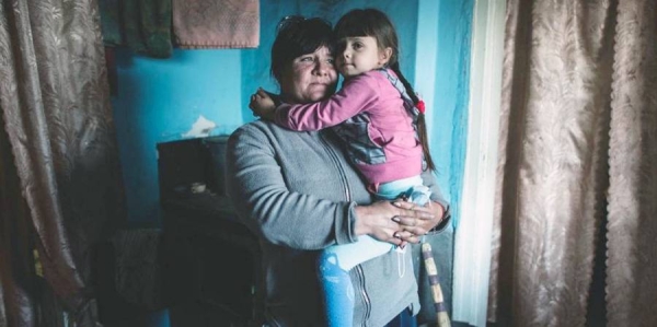 A woman holds her daughter in her house located right at the “contact line” in Ukraine. (file) — courtesy UNOCHA/Yevhen Maloletka
