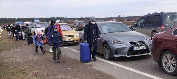 On 27 February 2022, as military operations continue, people fleeing Ukraine walk along vehicles lining up to cross the border from Ukraine into Poland.