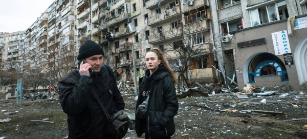 A man calls relatives standing in front of an apartment building heavily damaged during the ongoing Russian bombing in Kyiv, Ukraine.