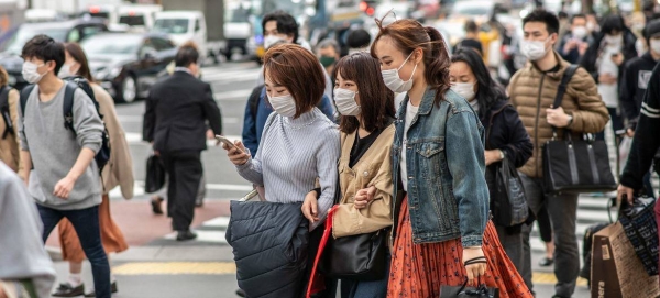 People with protective masks walk in the street of Tokyo, Japan.