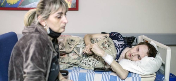 On March 3, 2022, a woman sits beside the stretcher of her son, who has been receiving treatment for three weeks at a hospital in Kiev, Ukraine. — courtesy UNICEF/Oleksandr Ratushniak