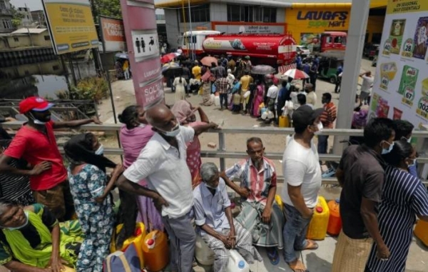 People wait in a long queue to buy kerosene at a fuel station in Colombo .