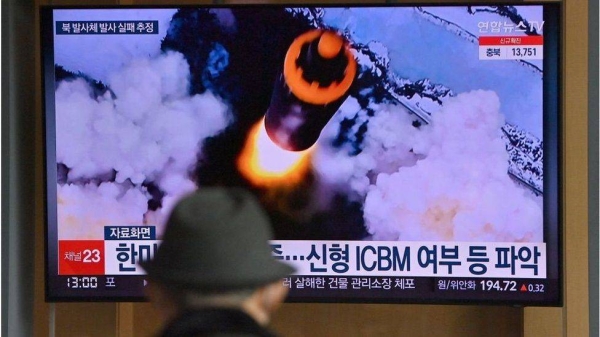 People watch a television screen showing a news broadcast with file footage of a North Korean missile test, at a railway station in Seoul on March 16.