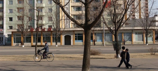 Children and adults pass a high-rise apartment building in the capital of DPRK, Pyongyang (file photo).