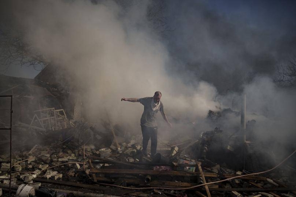 A man walks on the debris of a burning house, destroyed after a Russian attack in Kharkiv, Ukraine, Thursday.