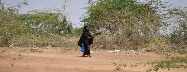 A mother and her child pass by carcasses of goats and sheep in Luuq, Somalia on 21 March 2022.